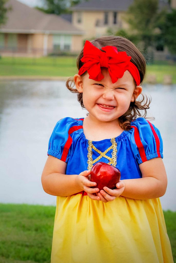 little girl in a Snow White dress up costume with an apple